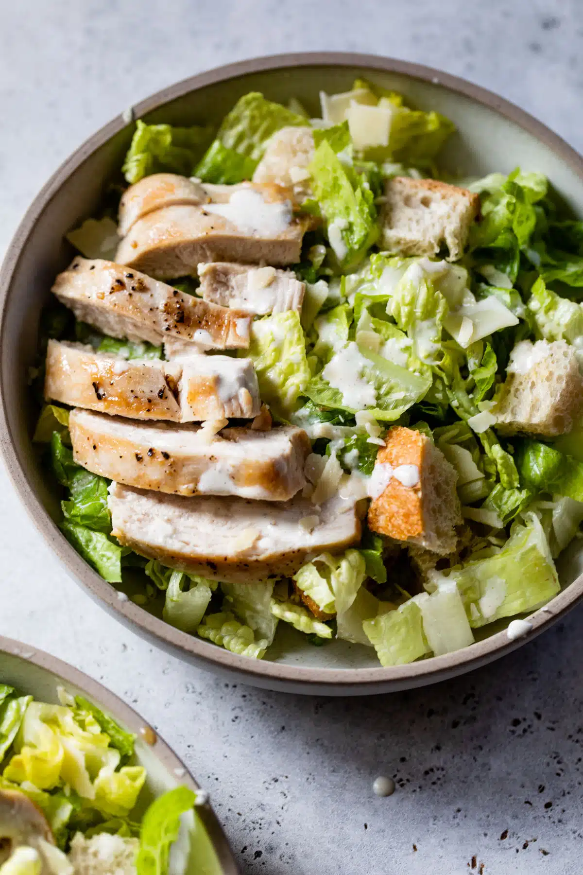 grilled chicken caesar salad in a bowl with dressing on top