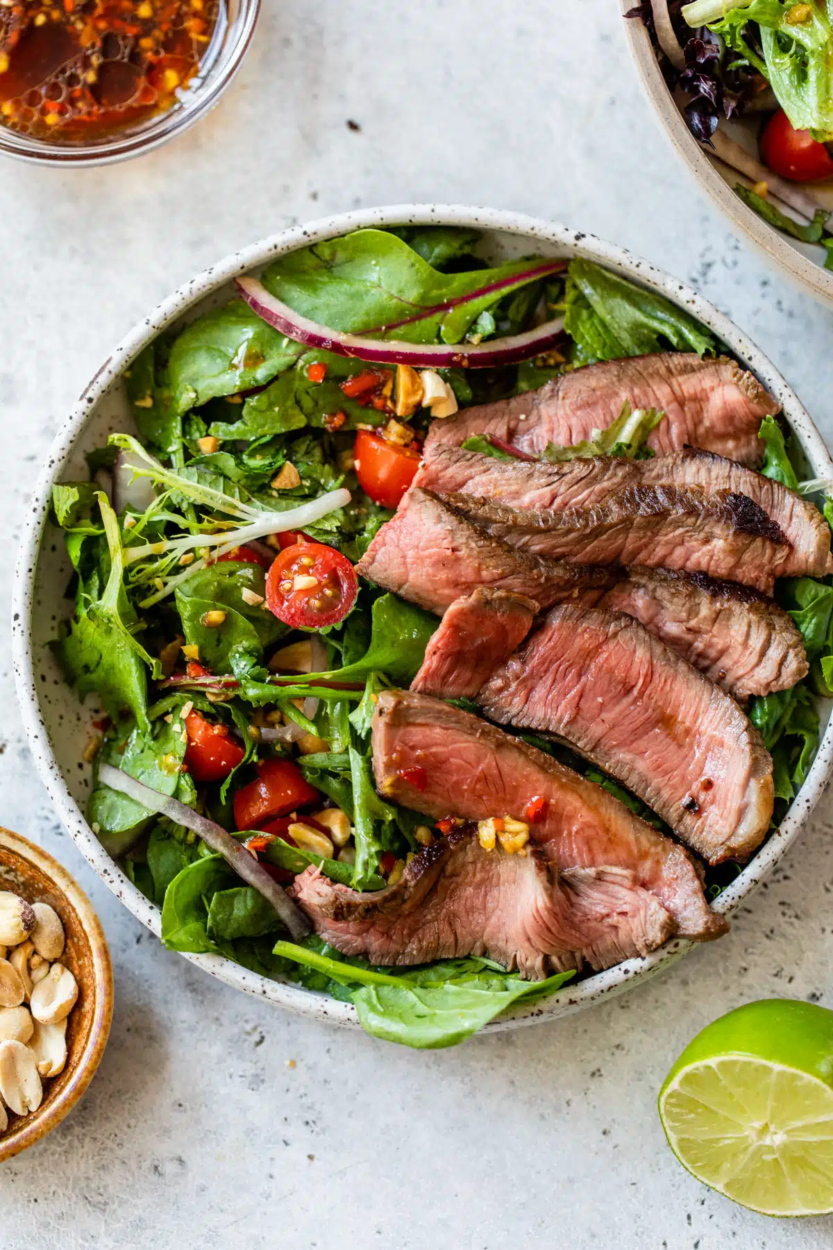 Thai steak salad in a bowl topped with sliced sirloin steak