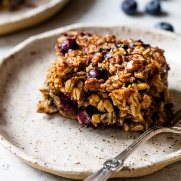 side view of a piece of blueberry baked oatmeal on a plate with a fork
