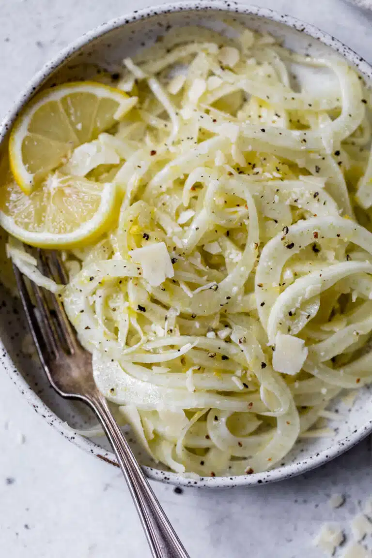 fennel salad on a plate with lemon slices and a fork