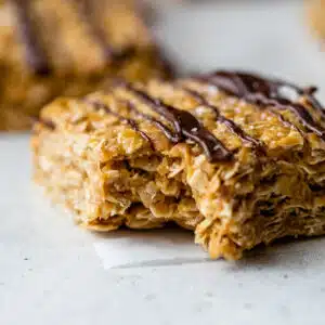 side view of a peanut butter oatmeal bar with melted chocolate drizzled over top with a bite taken out