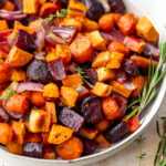 a medley of roasted root vegetables in a large white bowl.