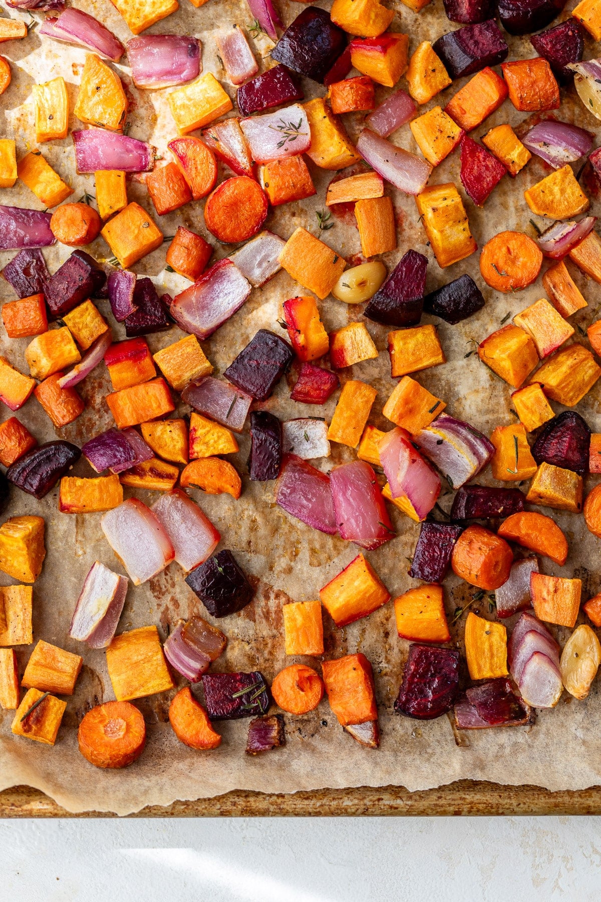 overhead view of a medley of roasted root vegetables on a sheet pan.