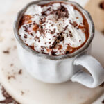overhead view of a mug of boozy hot chocolate topped with whipped cream and chocolate shavings.