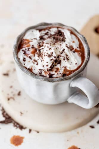 overhead view of a mug of boozy hot chocolate topped with whipped cream and chocolate shavings.