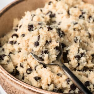 close up on a spoonful of chocolate chip cottage cheese cookie dough in a bowl.