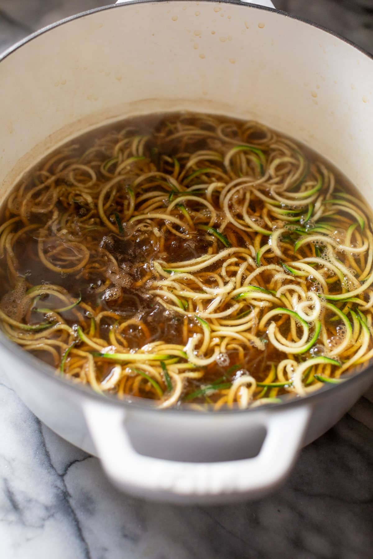 side view of zucchini noodles and kelp noodles in a large pot.