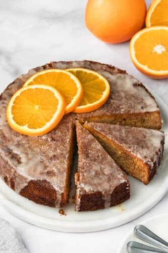 side view of a sliced orange cake on a white plate.