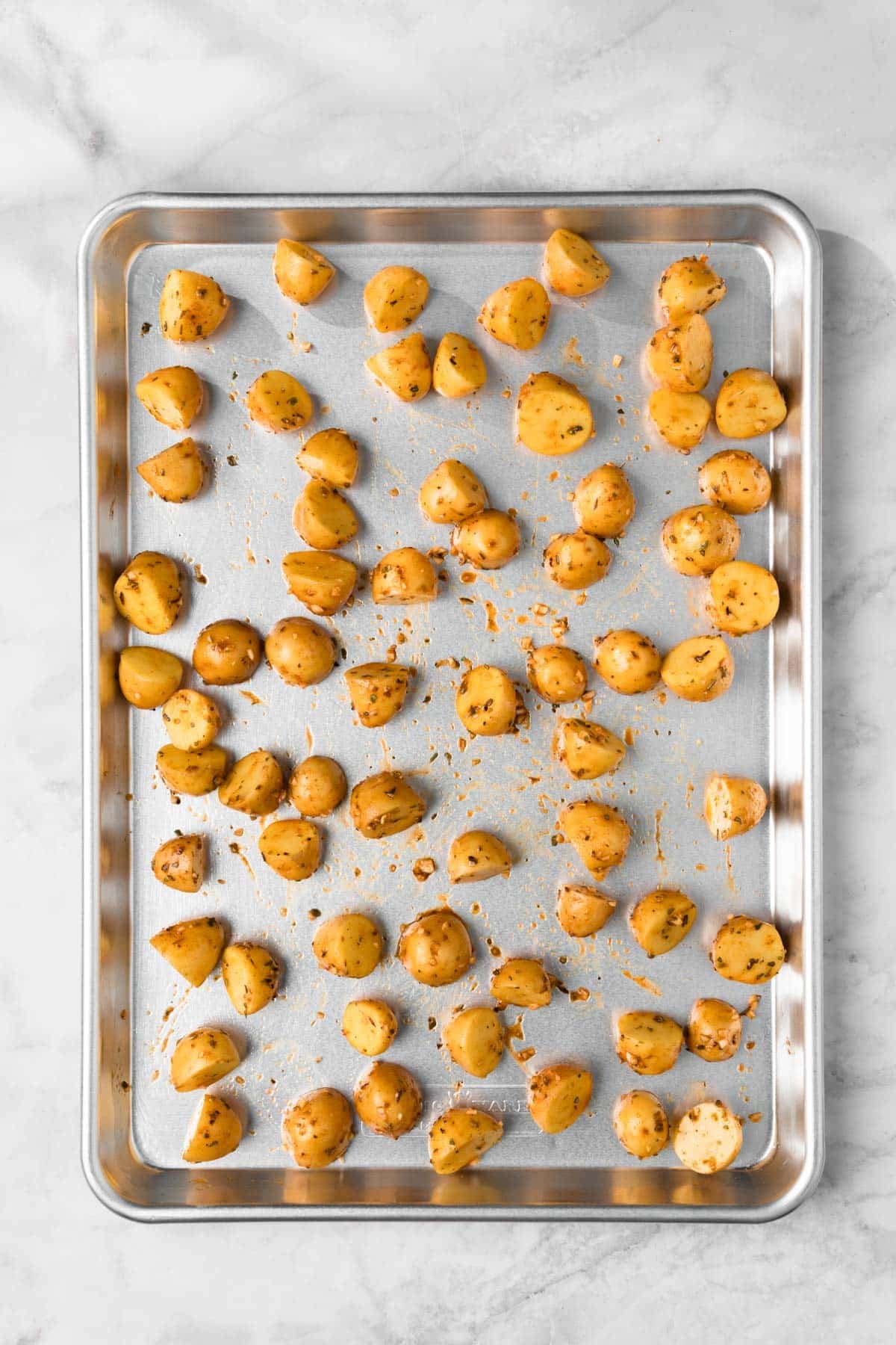 Overhead view of seasoned baby potatoes on a sheet pan.