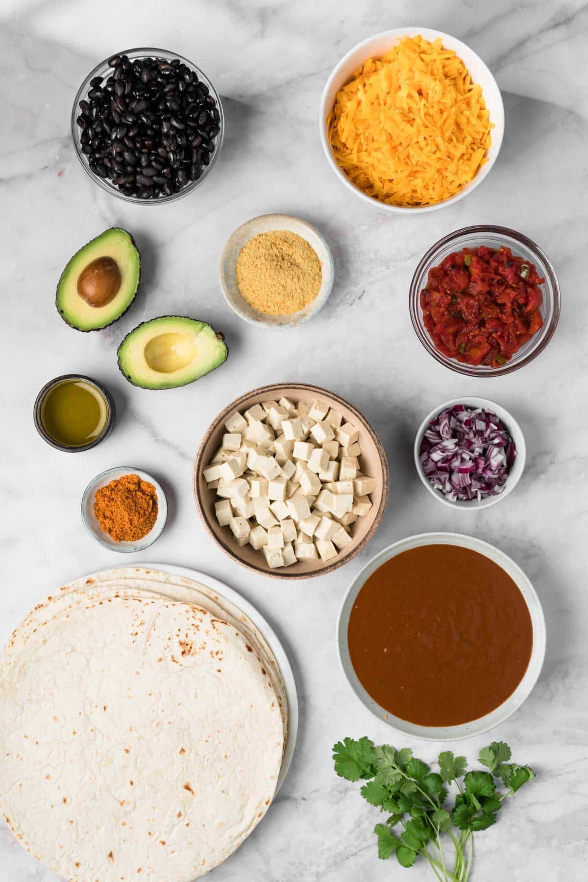 overhead view of the ingredients for tofu enchiladas in individual bowls.