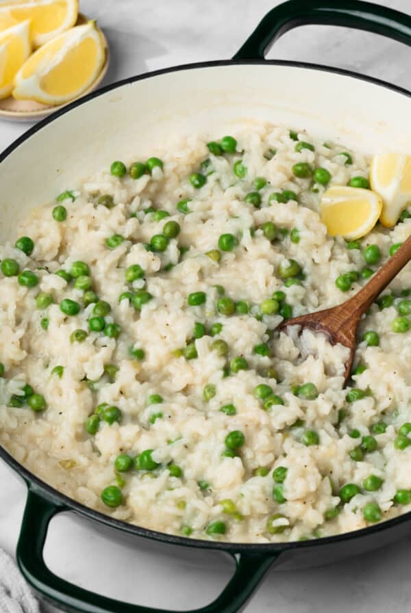 side view of a wooden spoon in a pot of baked risotto.