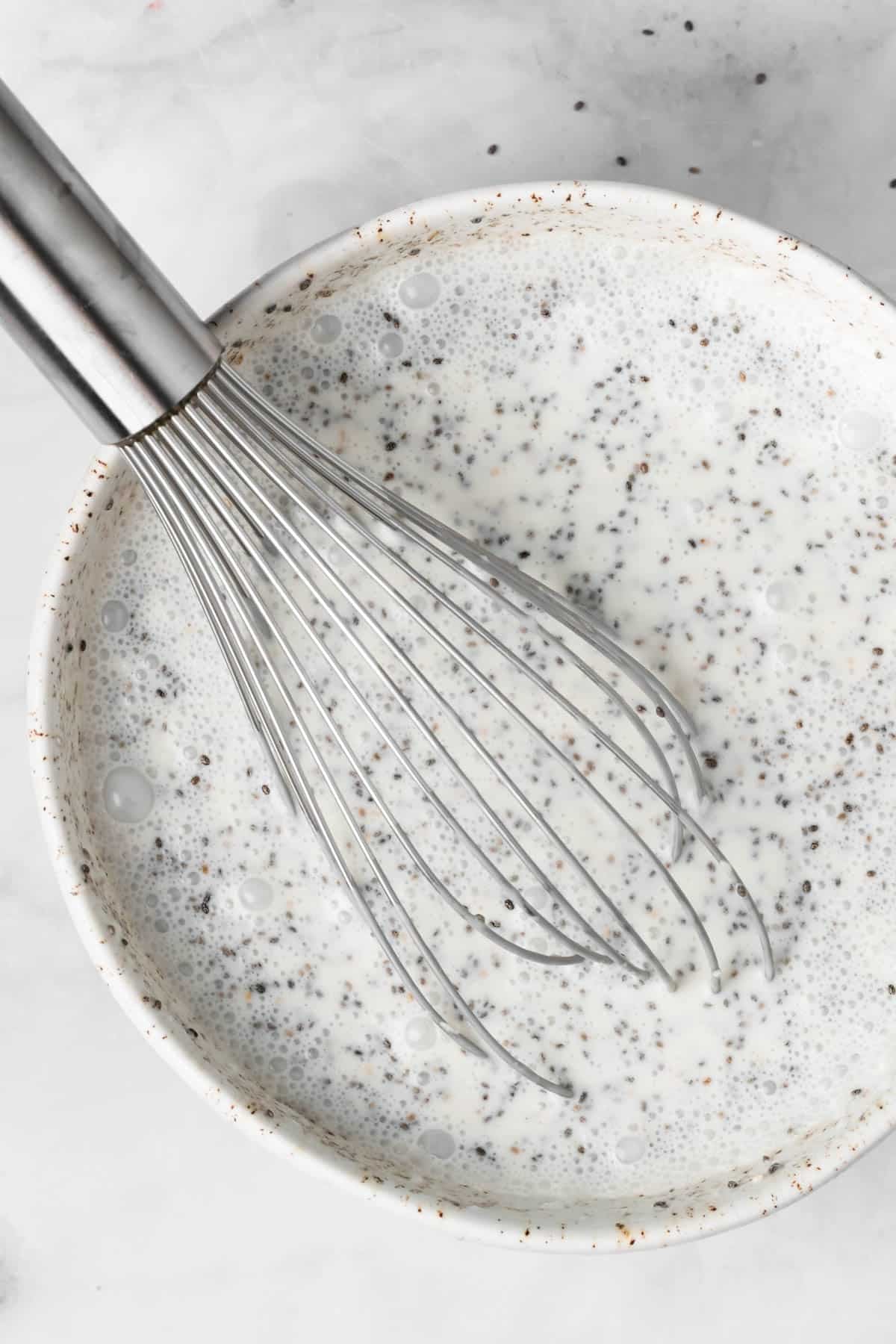 Overhead view of a whisk in a bowl of coconut chia pudding.