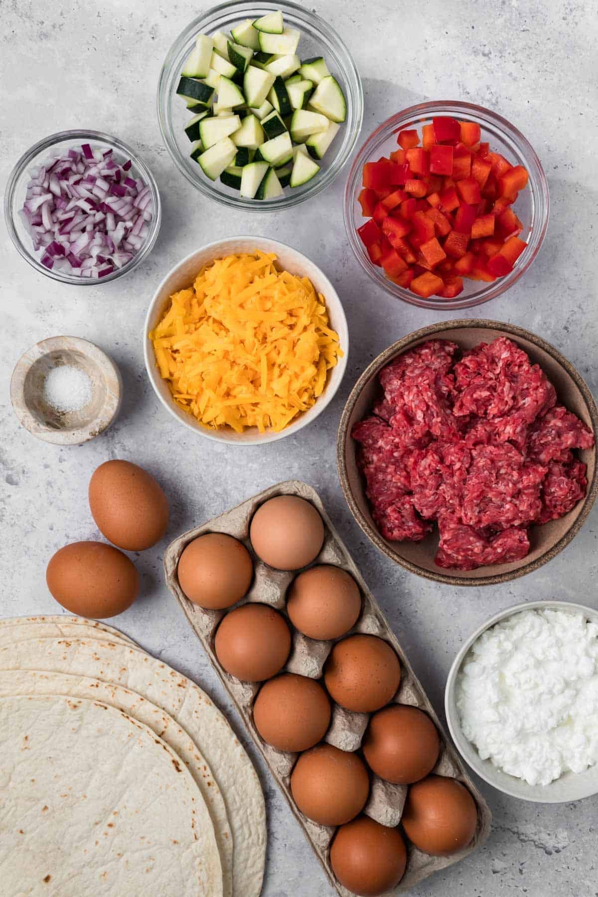 overhead view of the ingredients for breakfast burritos in individual bowls.