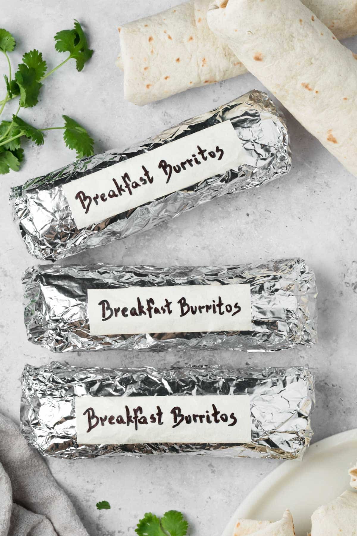 overhead view of labeled breakfast burritos wrapped in foil.