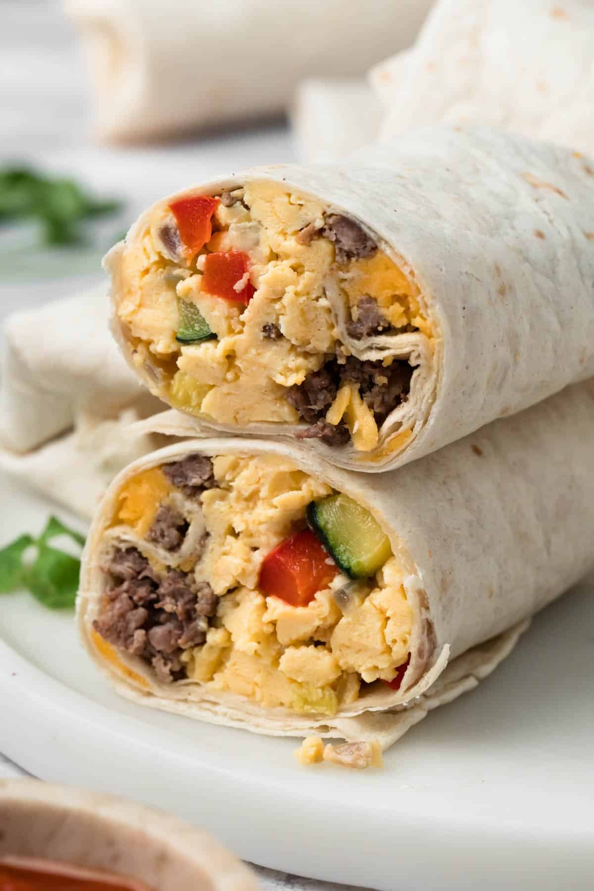 side view of a halved breakfast burrito on a plate.