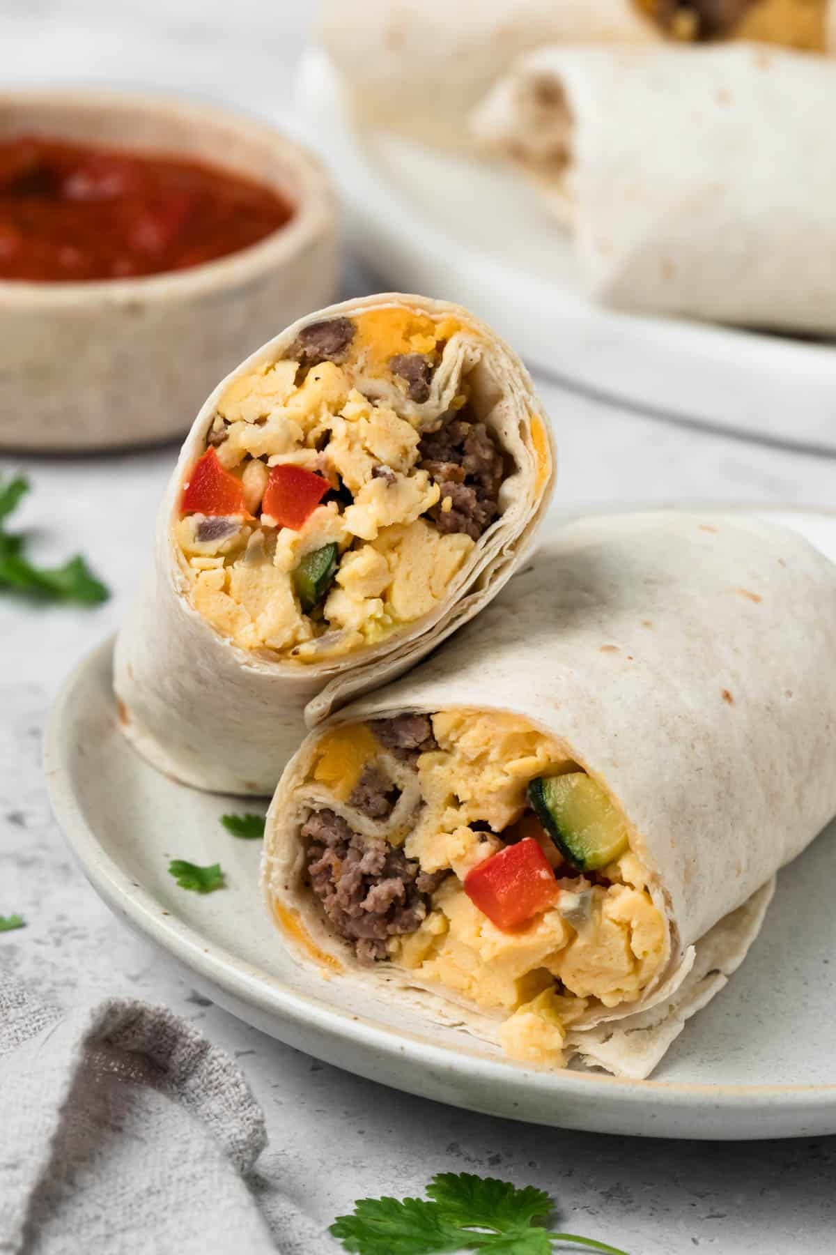 side view of a halved breakfast burrito on a plate.