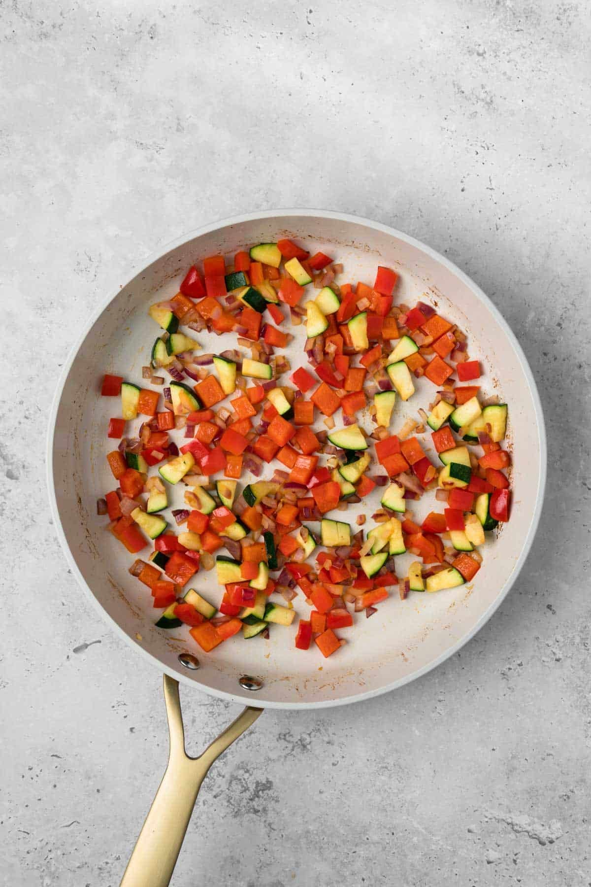 overhead view of cooked vegetables for breakfast burritos in a skillet.