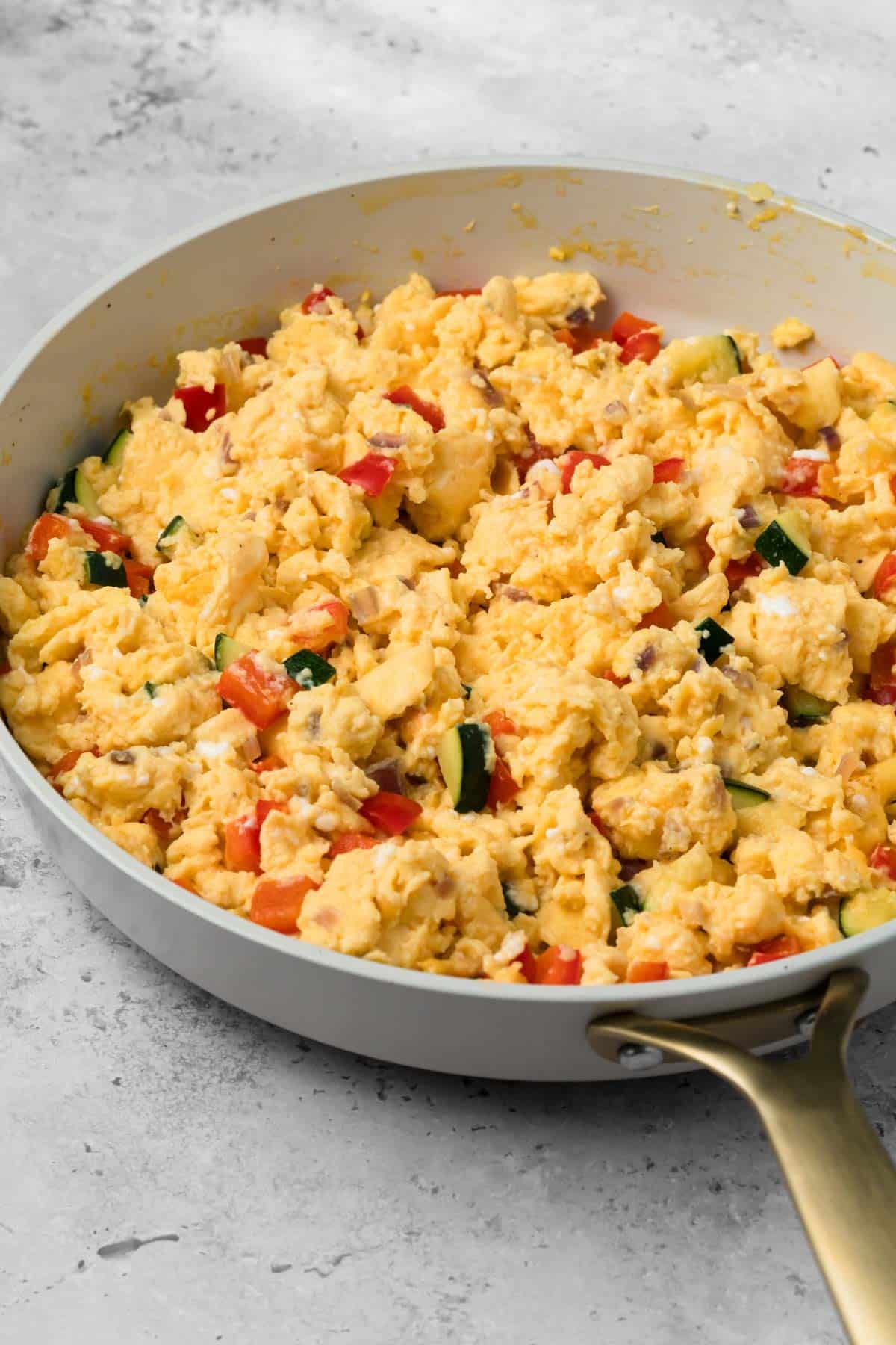 side view of a veggie egg scramble for breakfast burritos in a skillet.
