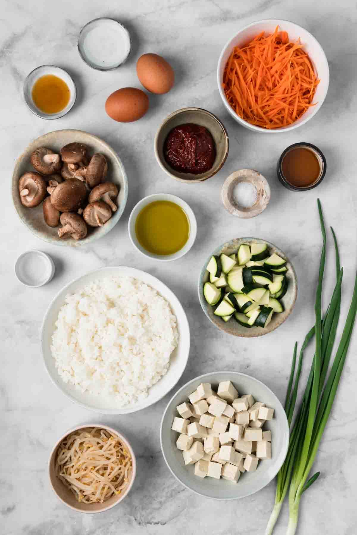 overhead view of the ingredients for tofu bibimbap in individual bowls.