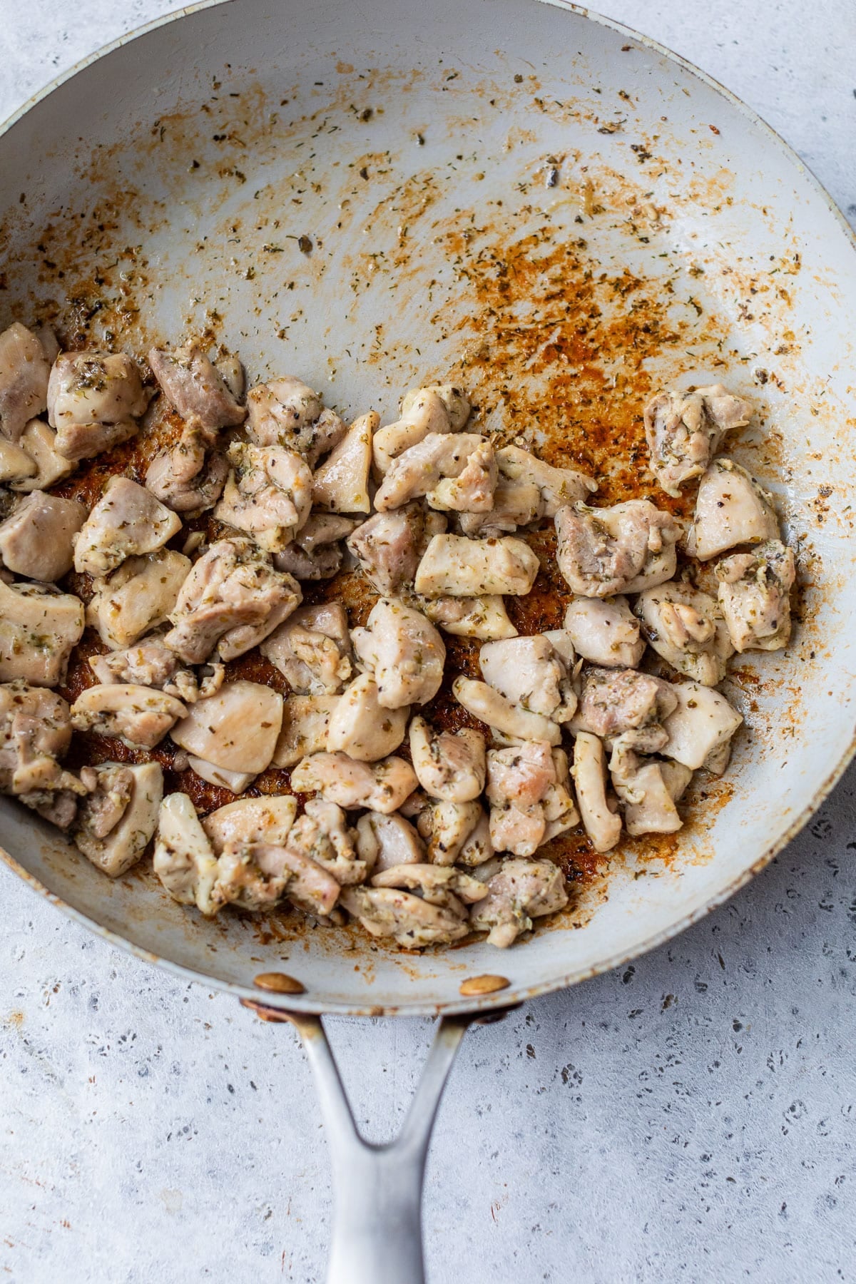 overhead view of cooked chicken thigh pieces in a skillet.