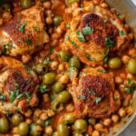 overhead view of Moroccan chicken thighs in a chickpea and olive sauce in a large pan.