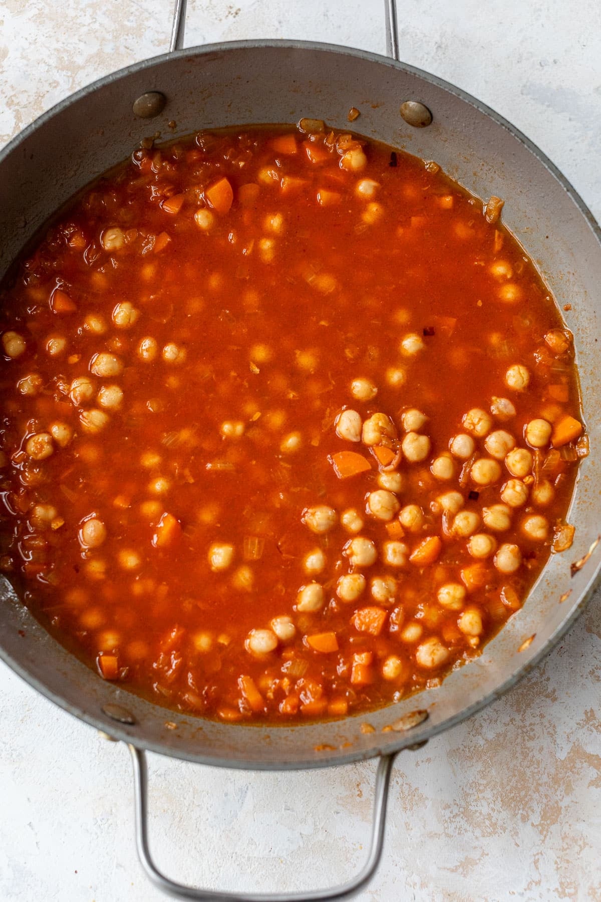 overhead view of a red chickpea sauce simmering in a skillet.
