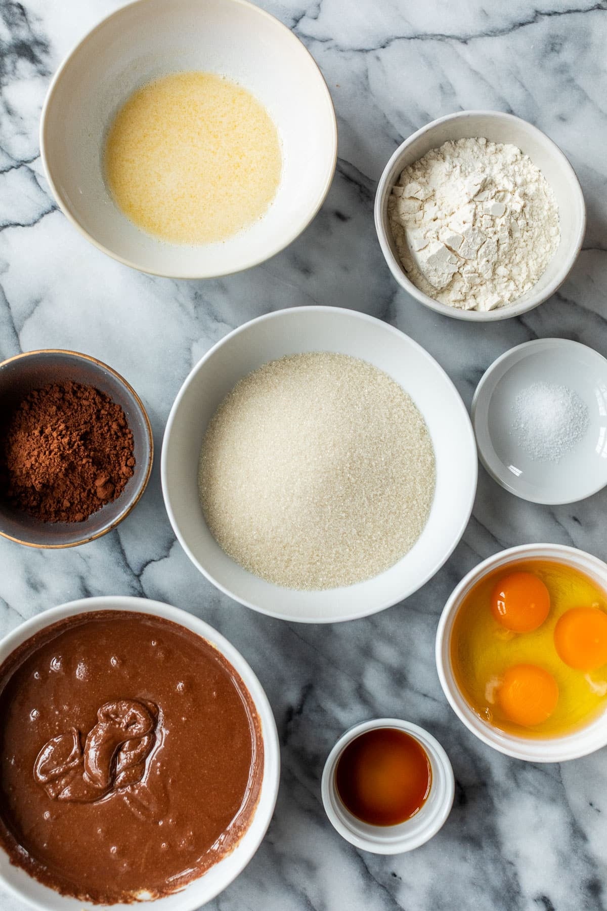 Overhead view of the ingredients for Nutella brownies in individual white bowls.
