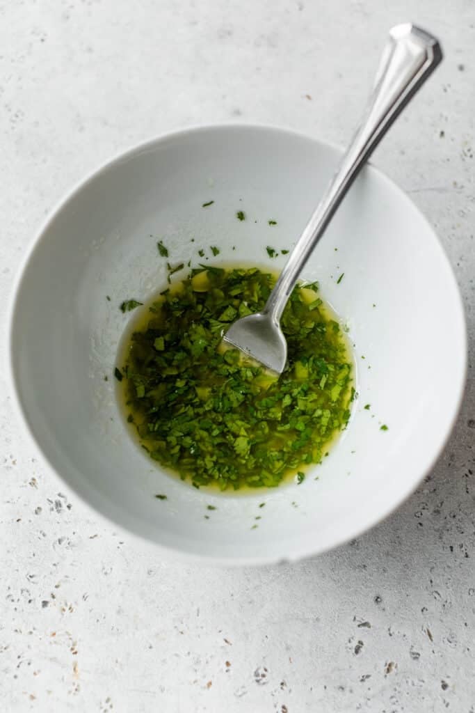 olive oil and fresh herbs in a white bowl with a fork
