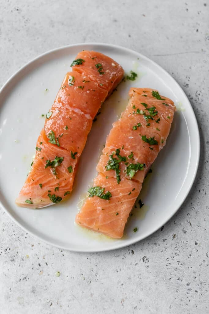 two pieces of marinated raw salmon on a white plate