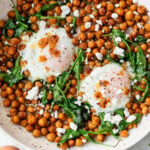 overhead view of cooked chickpeas, spinach, and 2 eggs topped with feta cheese in a skillet.