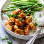 side view of healthy sesame chicken in a bowl with white rice and green beans.