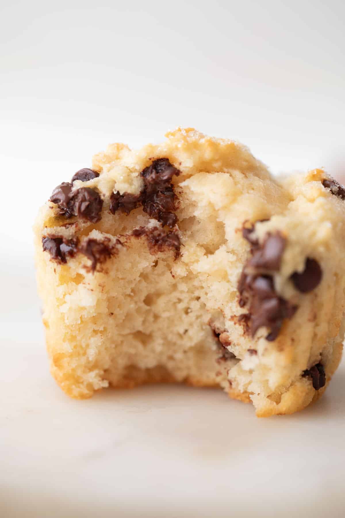 side view of a baked greek yogurt muffin with a bite taken out of it.