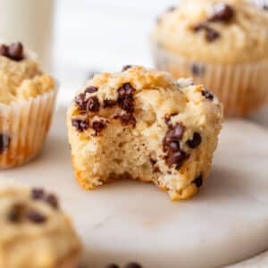 side view of a greek yogurt muffin with a bite taken out of it with more muffins in the background.