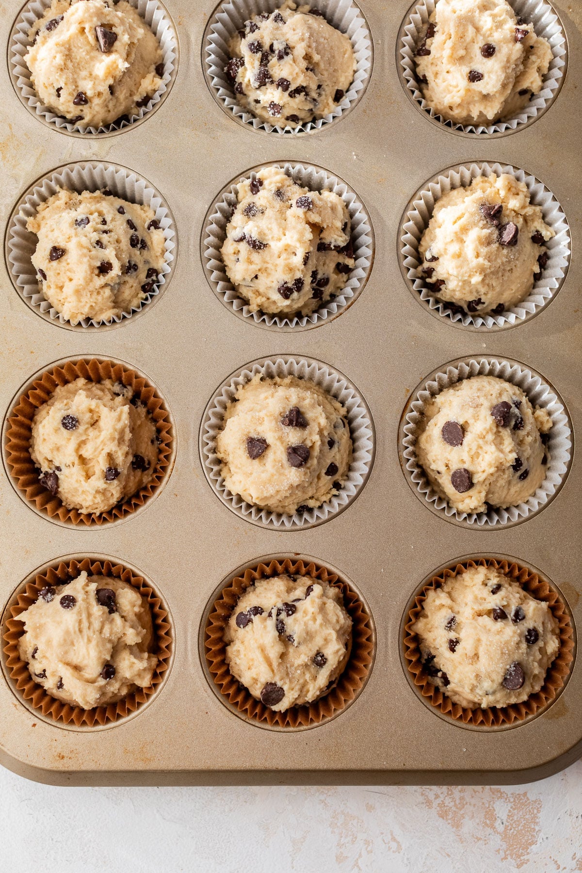 overhead view of raw greek yogurt muffin batter in a muffin tin.