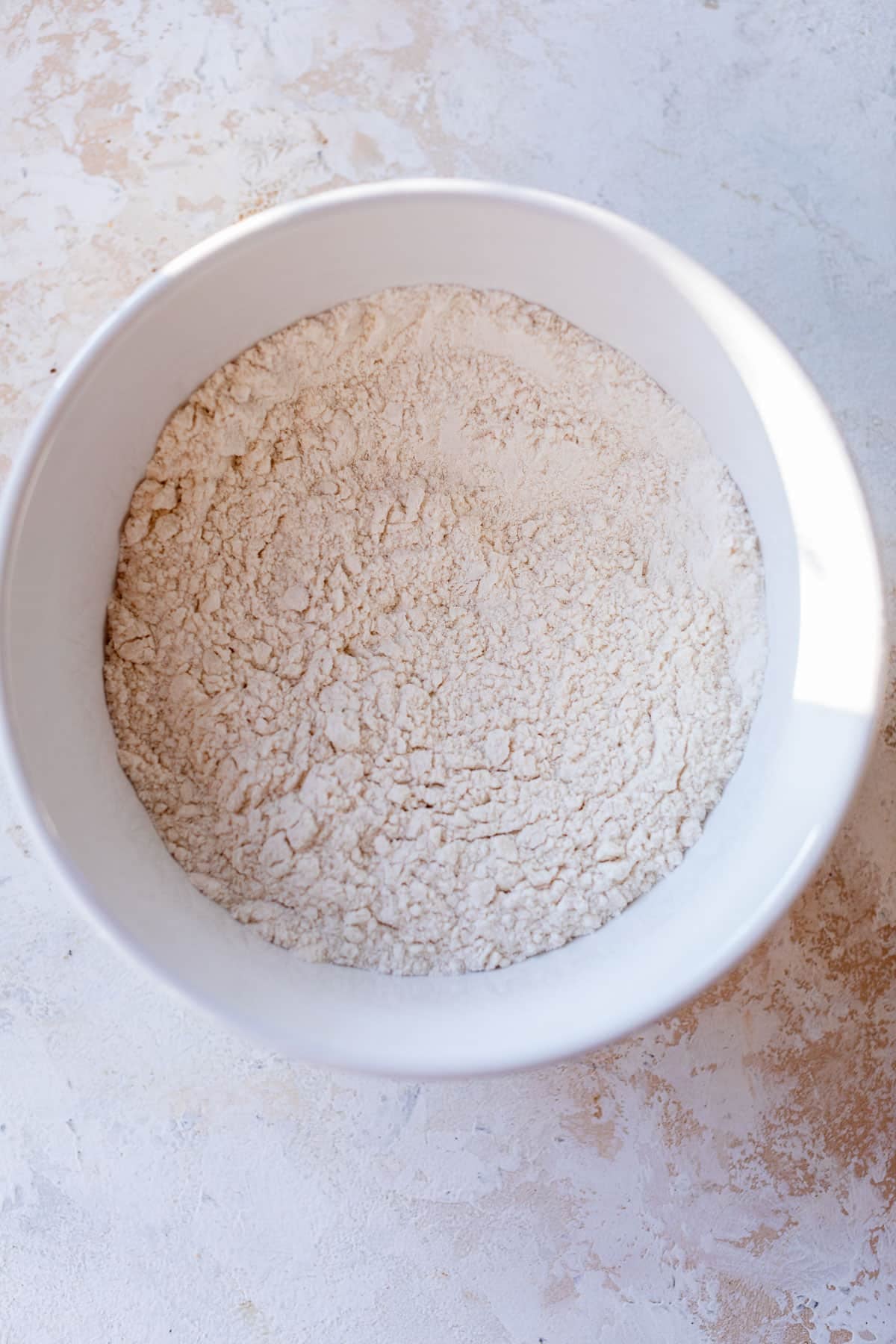 overhead view of the dry ingredients for greek yogurt muffins in a white bowl.