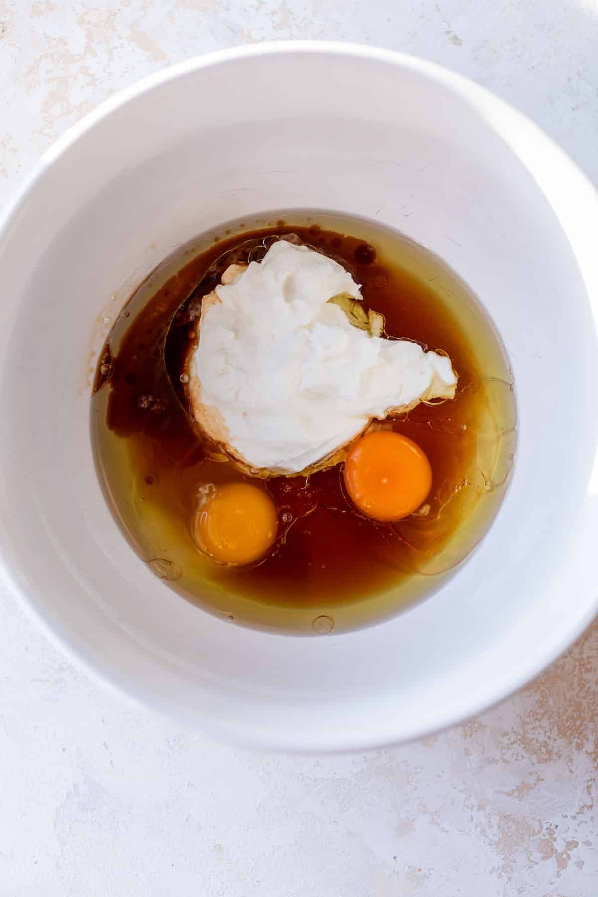 overhead view of the wet ingredients for greek yogurt muffins in a white bowl.