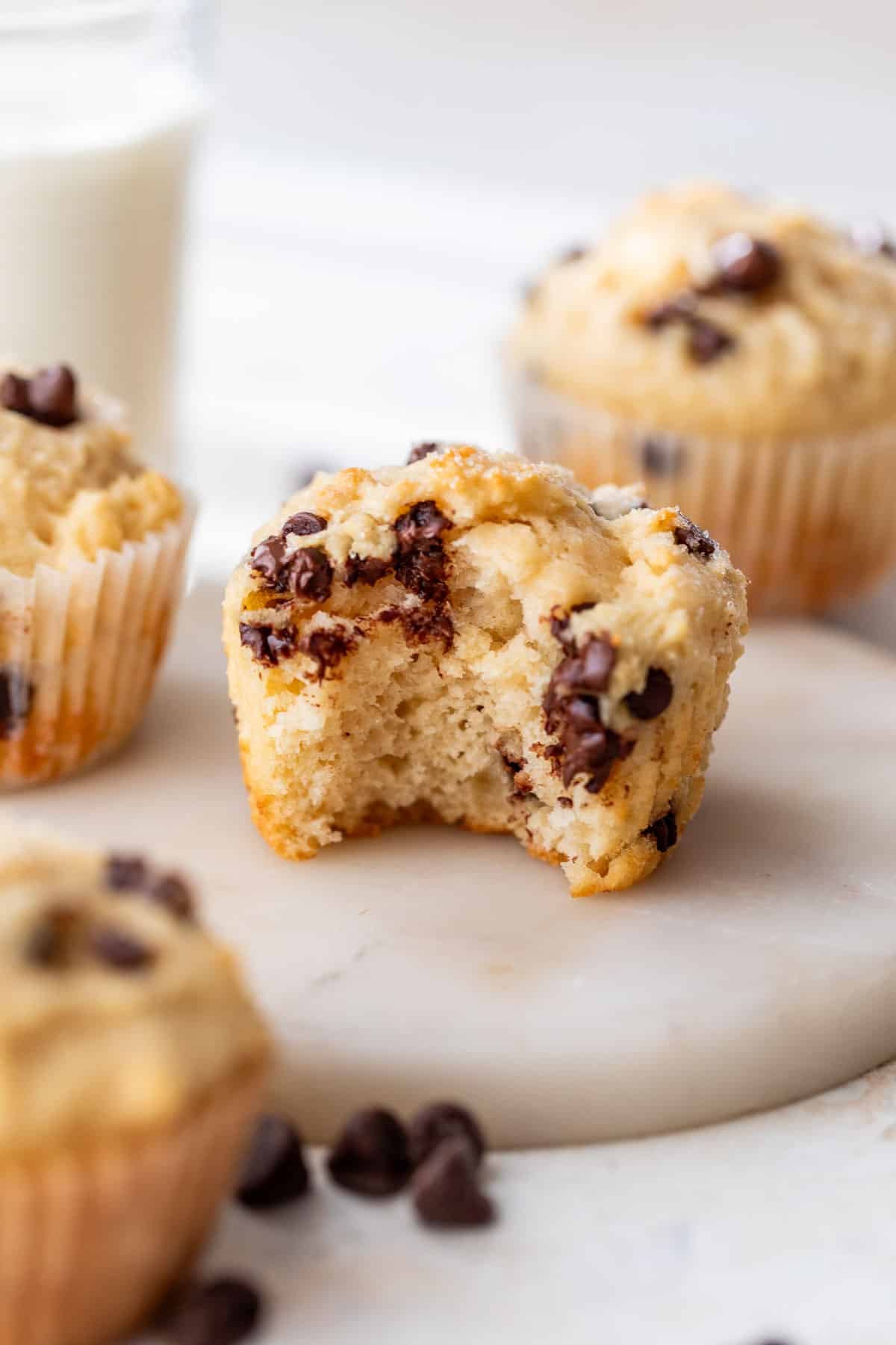 side view of a greek yogurt muffin with a bite taken out of it with more muffins in the background.