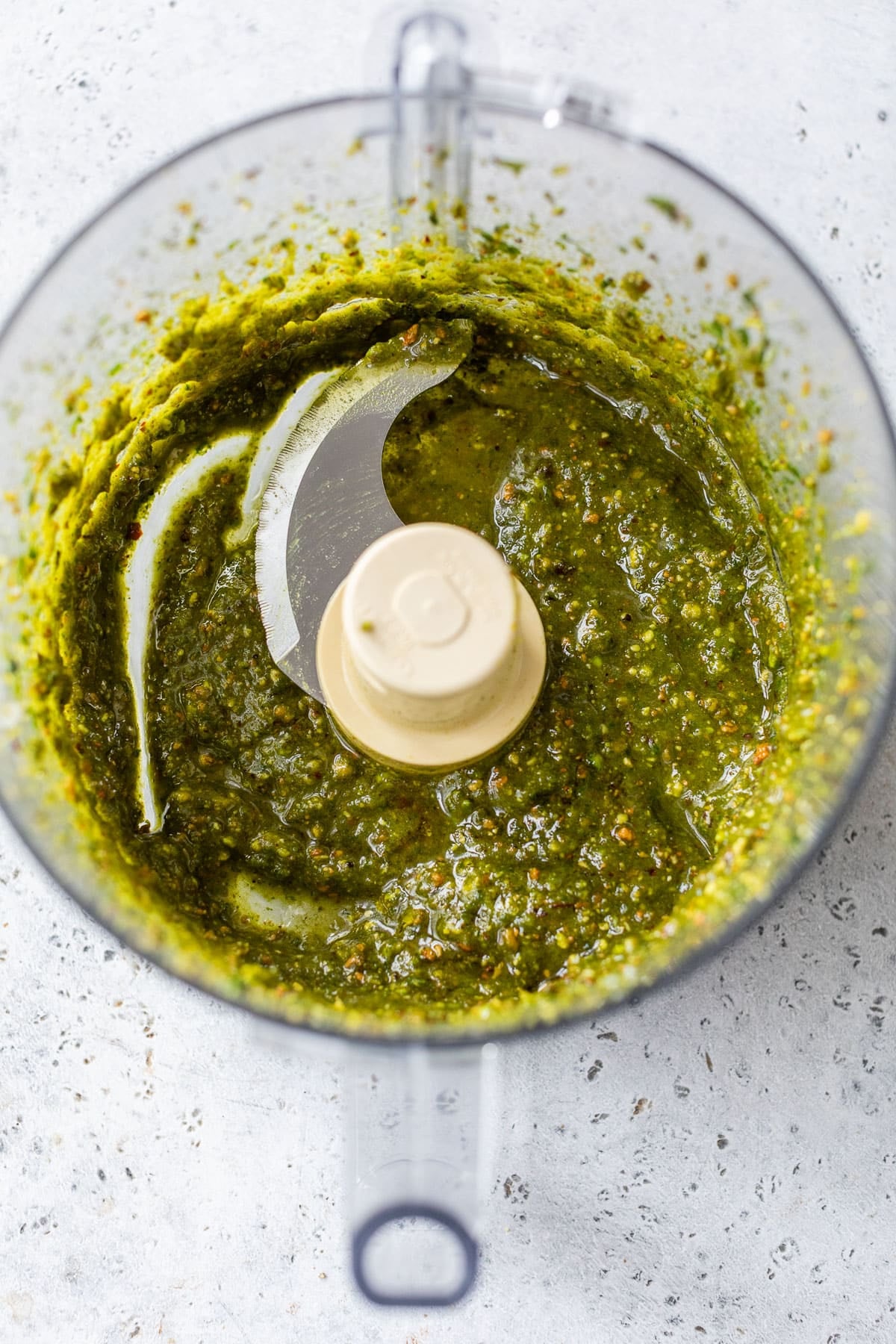 overhead view of blended pistachio pesto in a food processor.