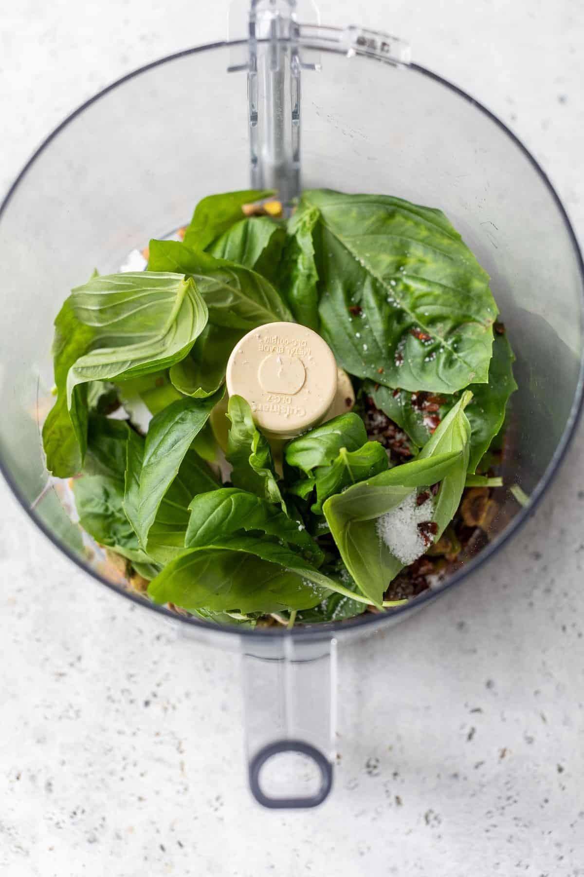 overhead view of the ingredients for pistachio pesto in a food processor.