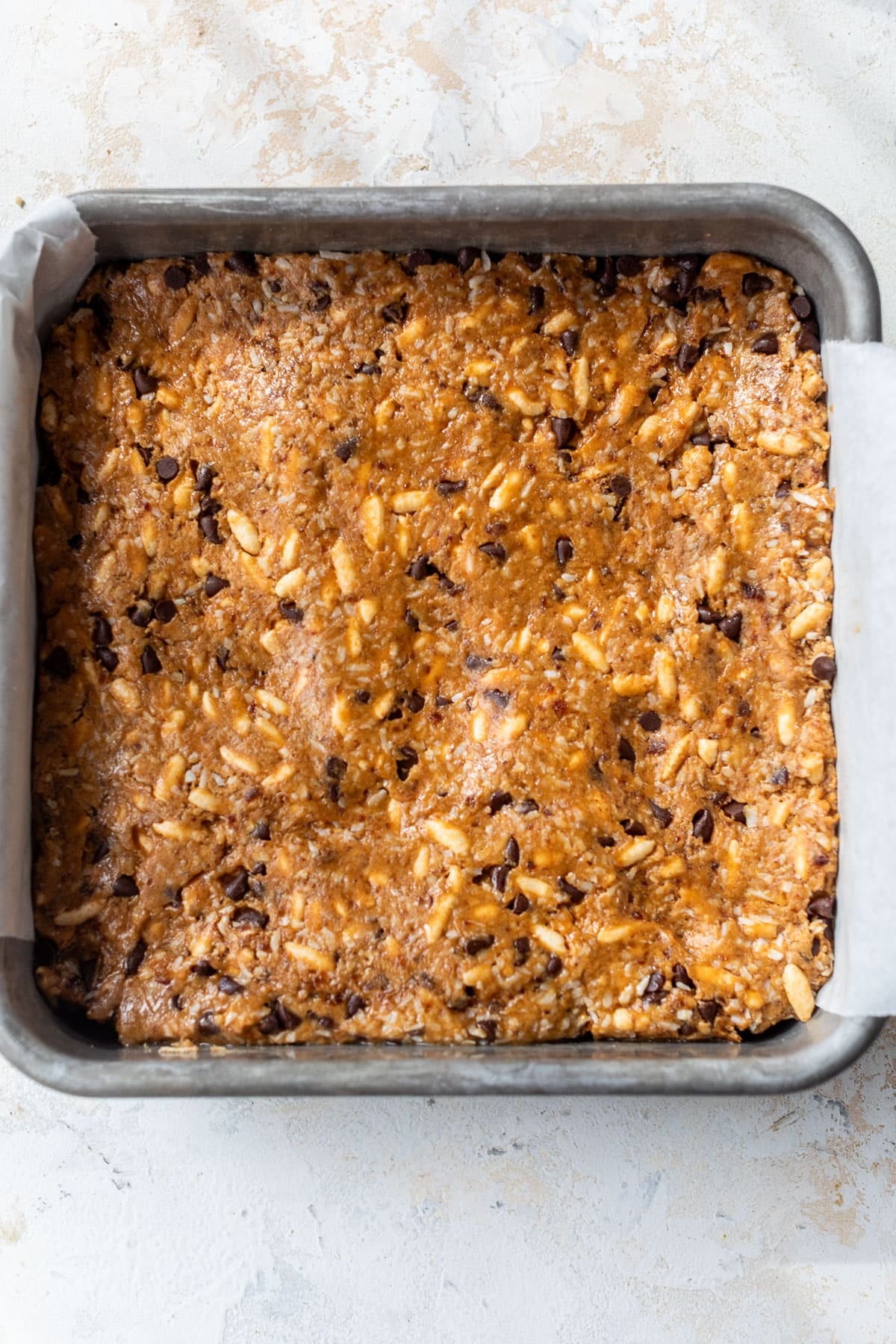 overhead view of the batter for puffed rice protein bars pressed into a baking dish.
