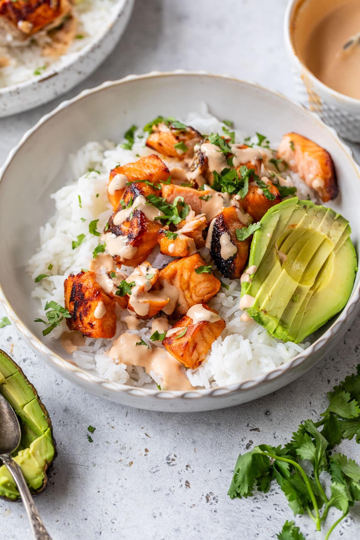side view of a honey chipotle salmon bowl topped with avocado and chipotle mayo.