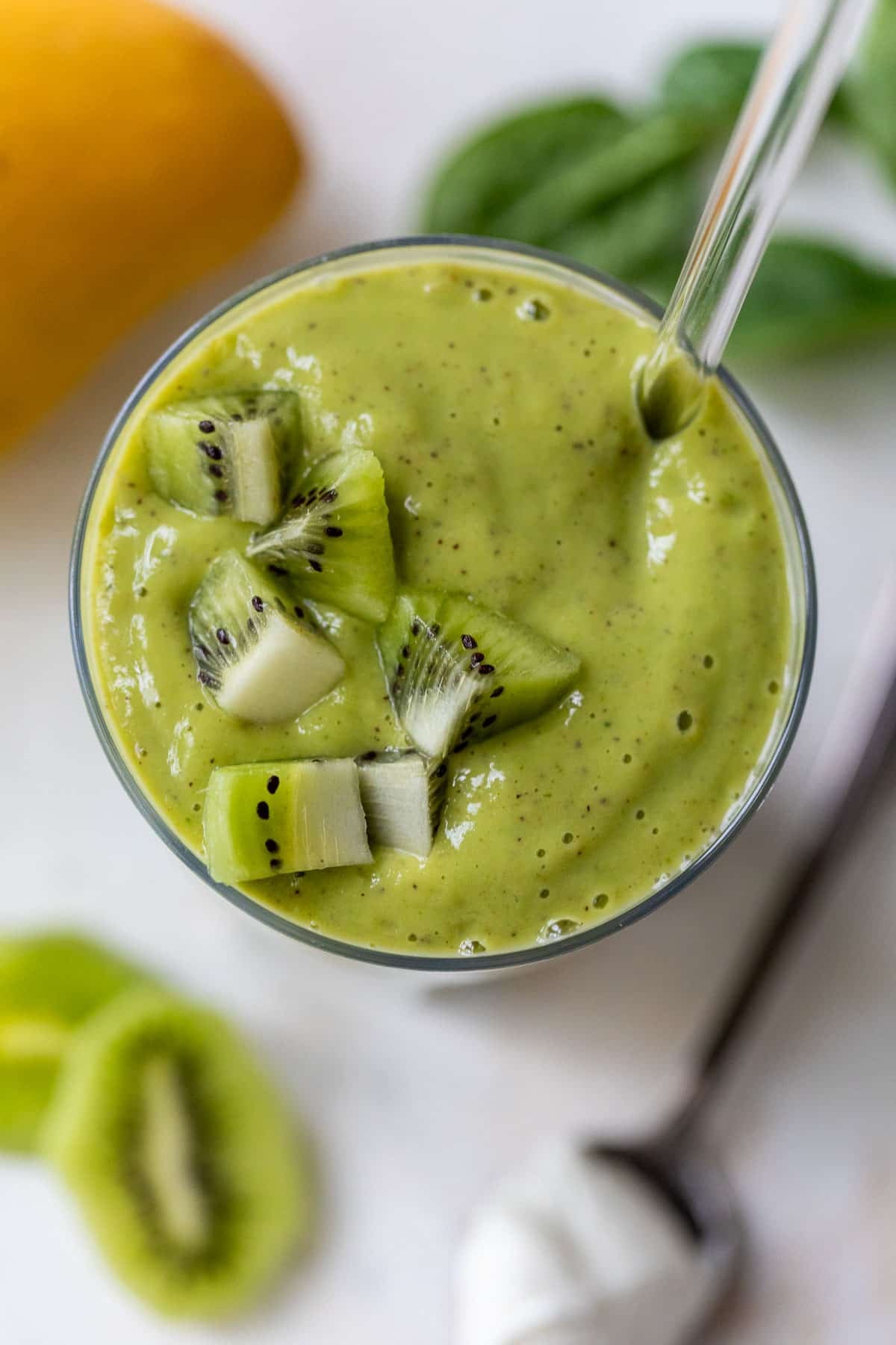 overhead view of a thick and green kiwi smoothie in a glass with chopped kiwi on top.