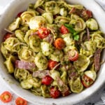 overhead view of a pesto-dressed tortellini pasta salad in a large white bowl.