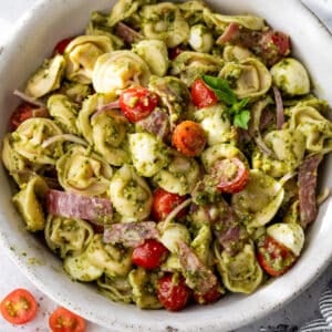 overhead view of a pesto-dressed tortellini pasta salad in a large white bowl.