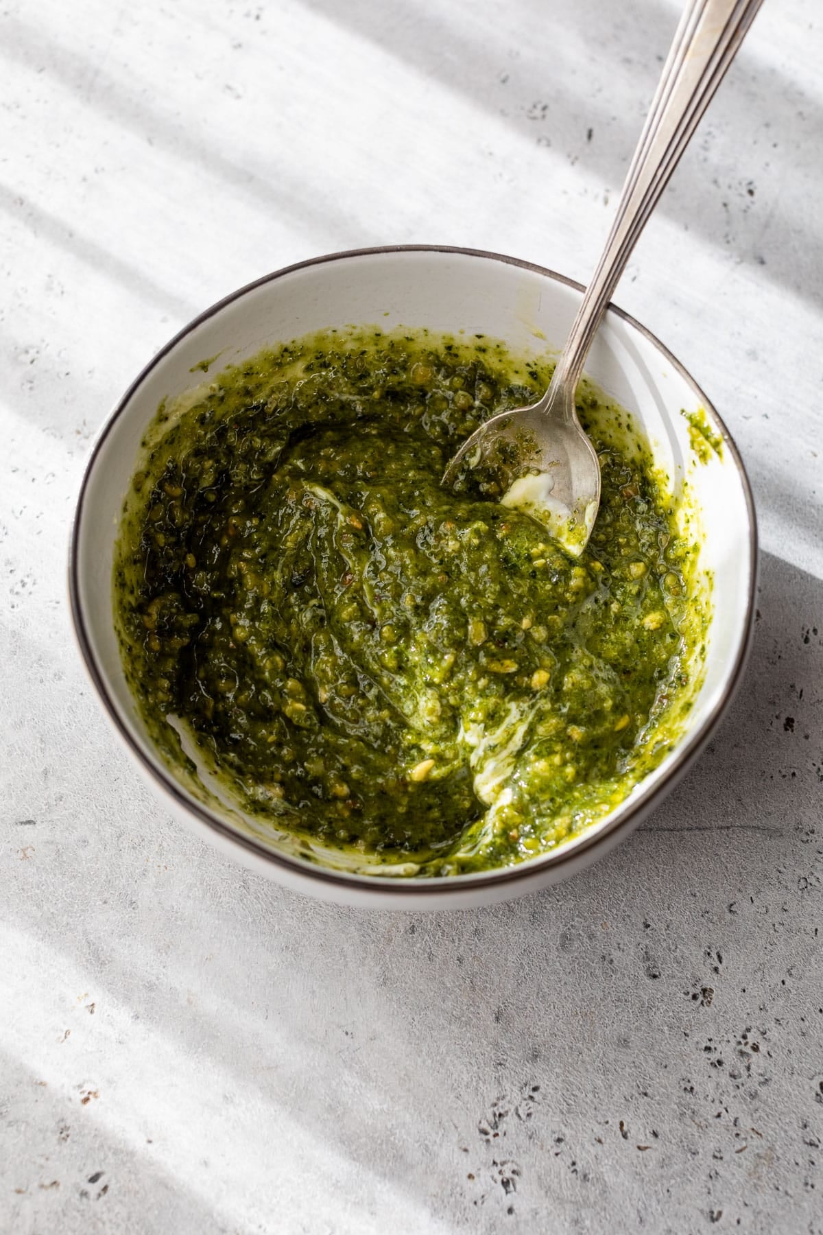 overhead view of the pistachio pesto sauce for a tortellini pasta salad in a small bowl.