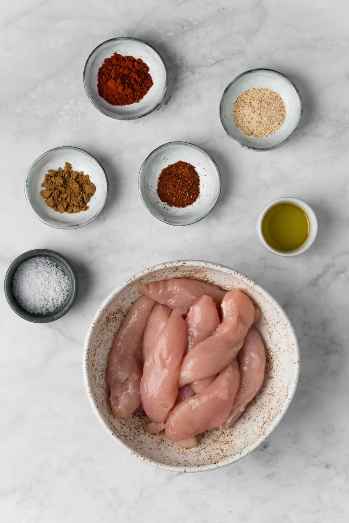 overhead view of the ingredients for grilled chicken tenders in individual bowls.