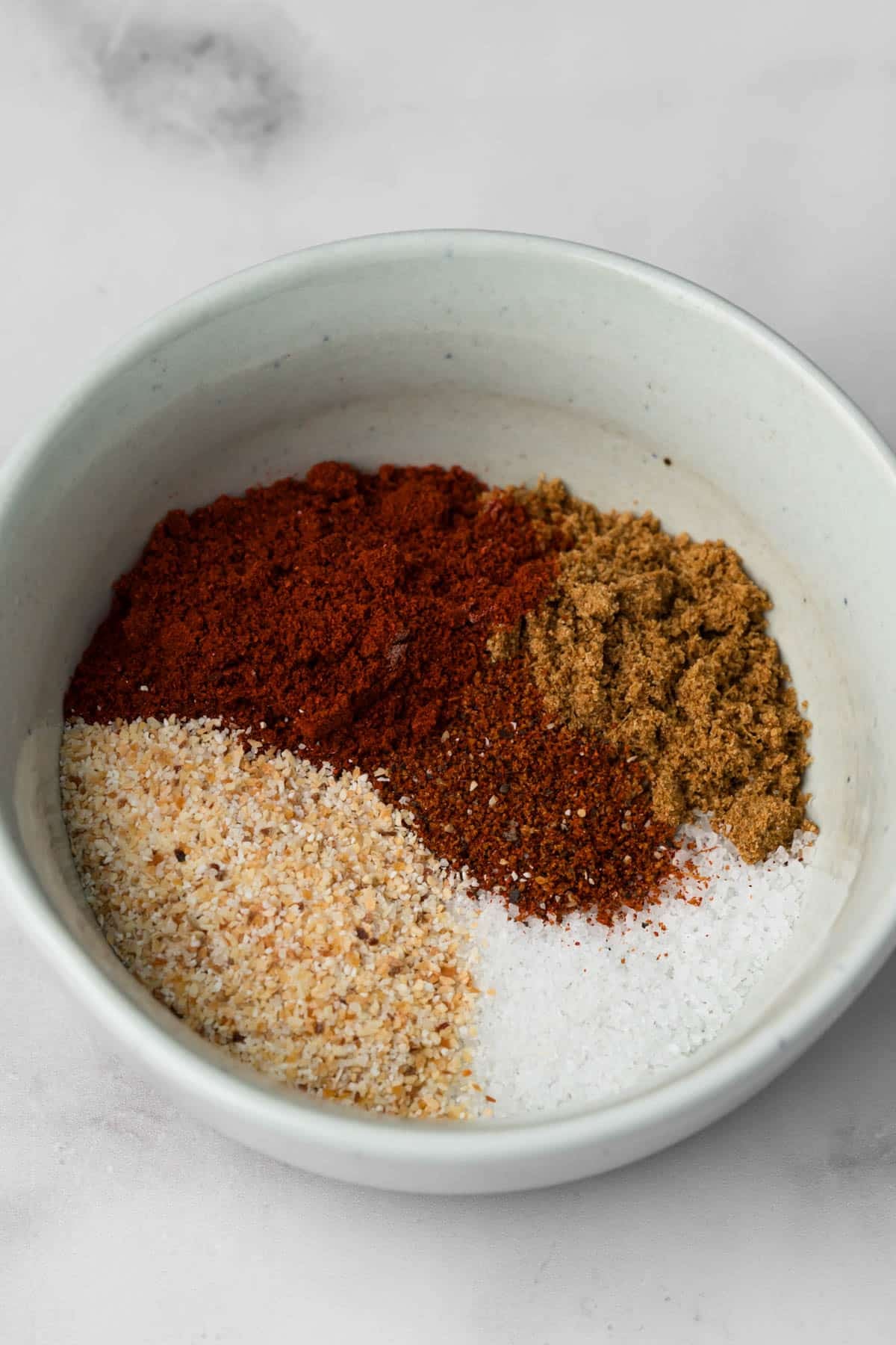 side view of the seasonings for grilled chicken tenders in a small bowl.
