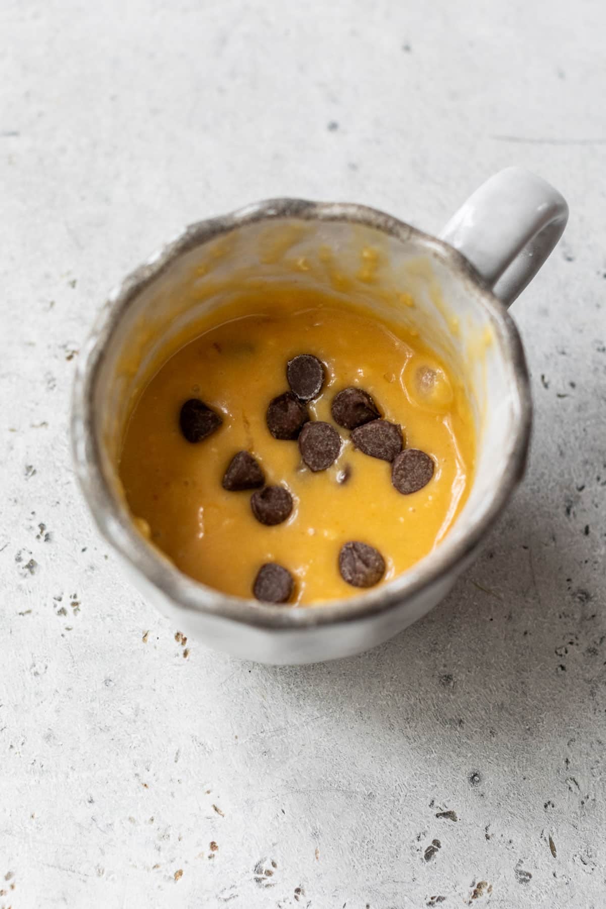 overhead view of the chocolate chip cake batter for a chocolate chip mug cake in a mug.