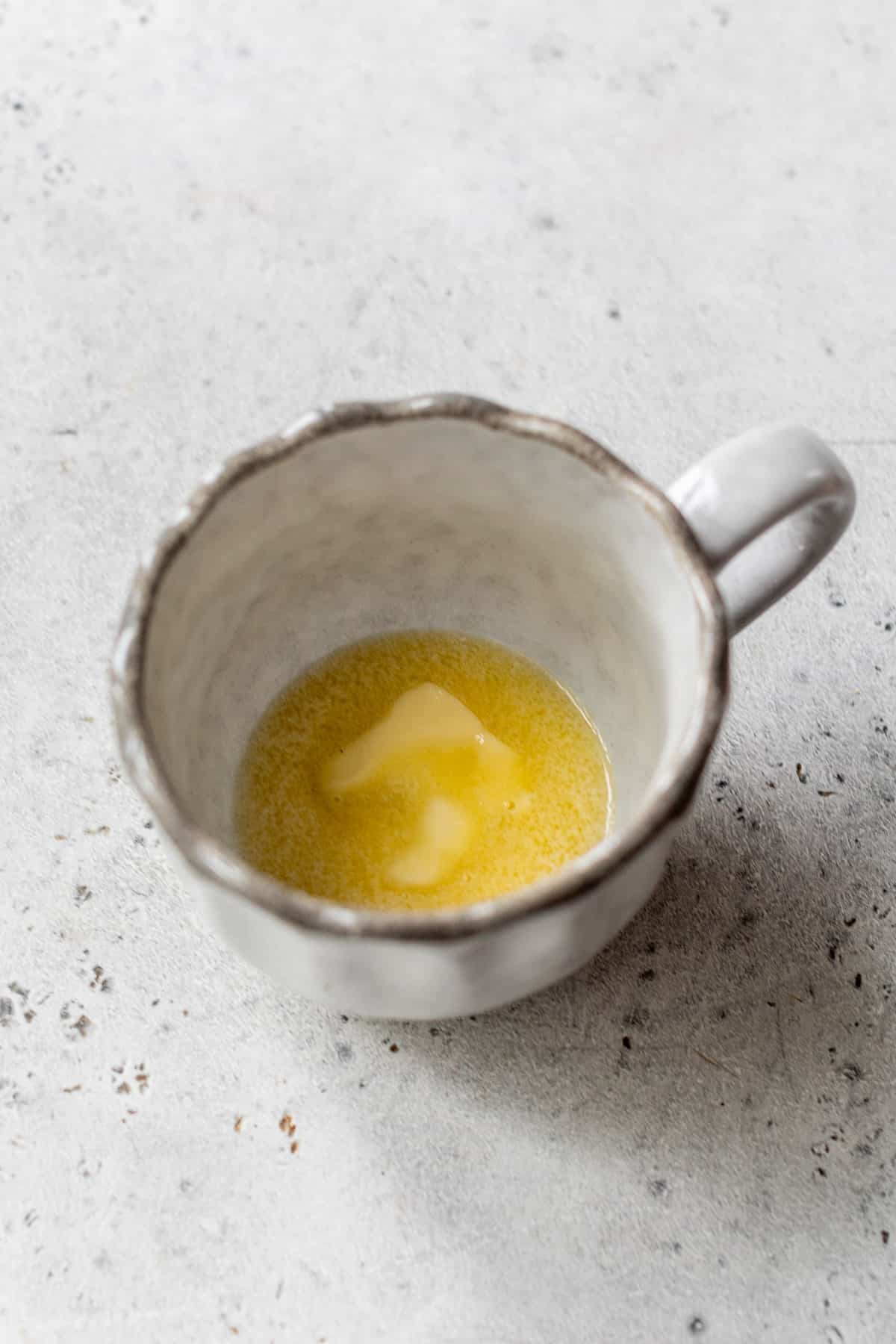 overhead view of partially melted butter in a mug.