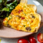 side view of a slice of tortilla quiche next to a salad on a plate.